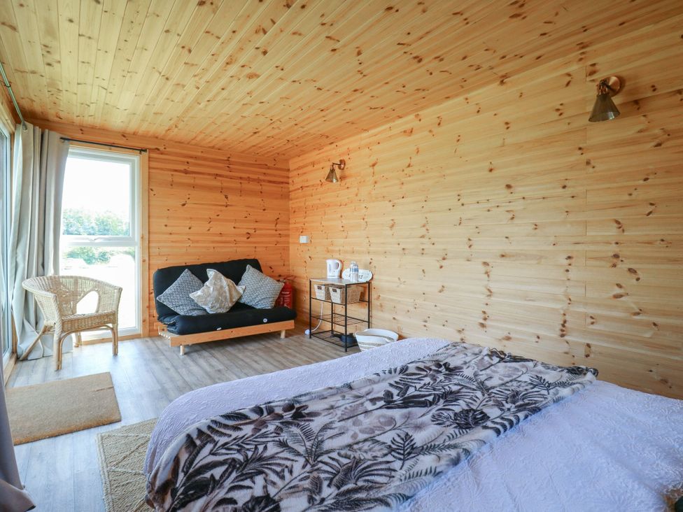 A bedroom with a bed and sofa at Bluebell Lodge in Hastings