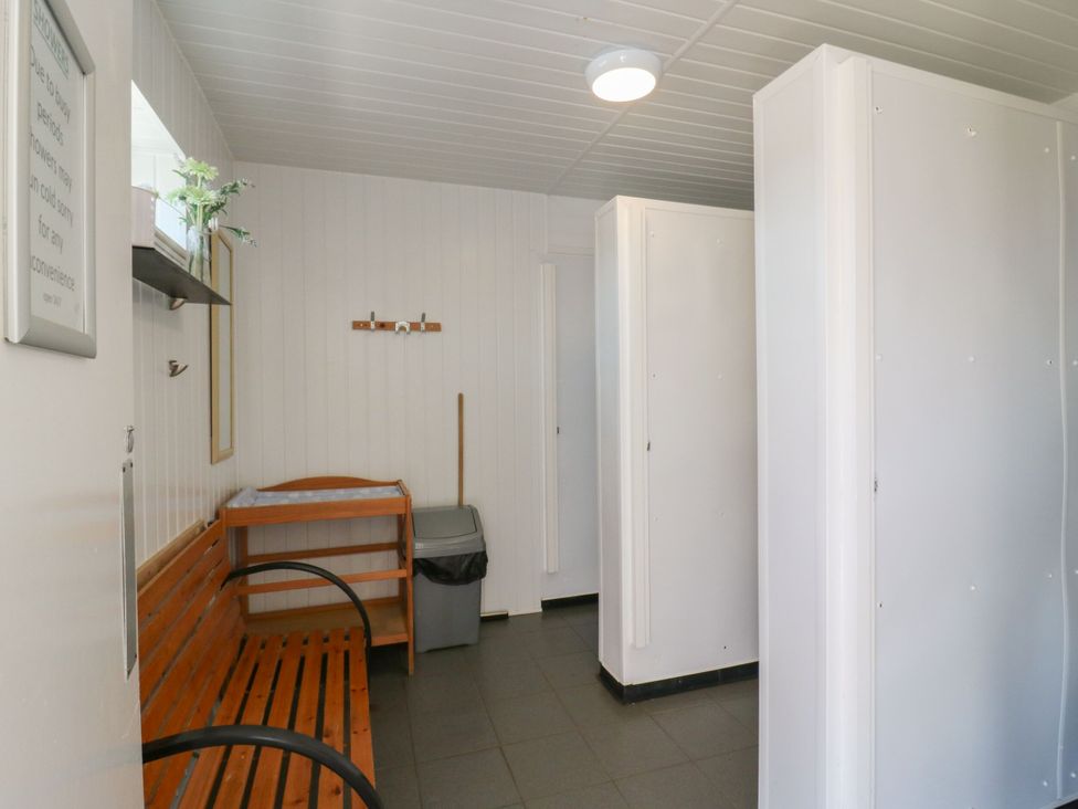 A hallway with a bench and trash can at Bluebell Lodge in Hastings