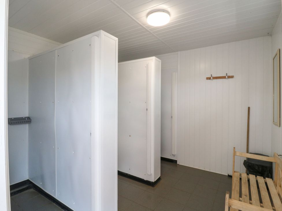 A shower room with cubicles and a bench at Bluebell Lodge in Hastings