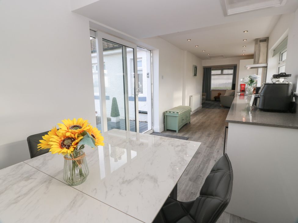 A kitchen with a dining table and sliding doors at Marchdyke Farm Cottage, Dalton near Annan