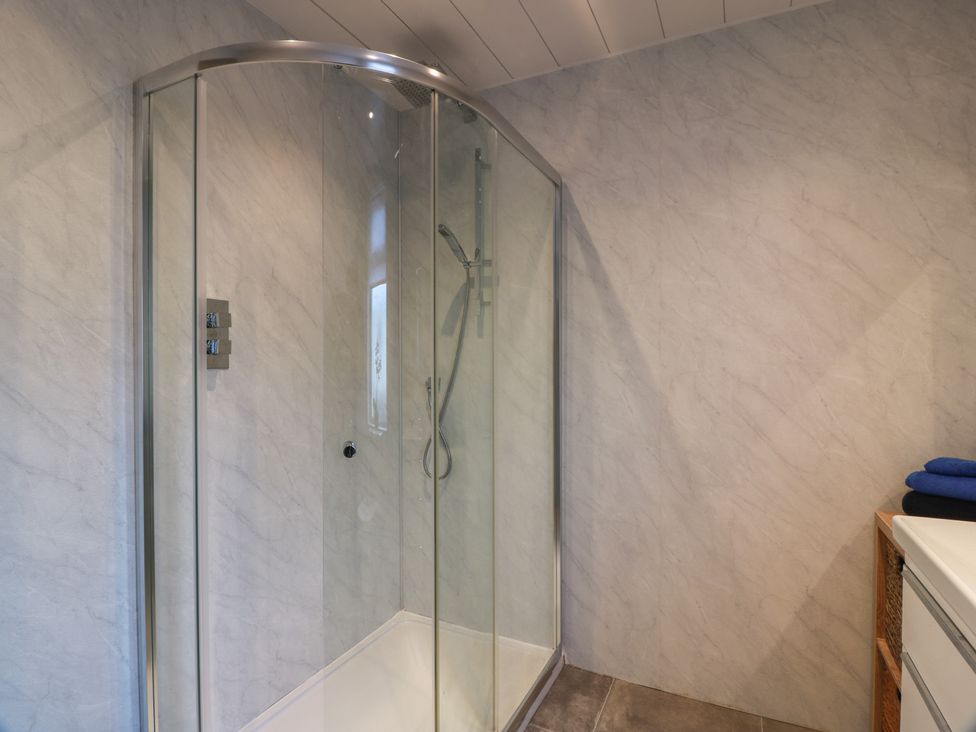 A shower with glass door and a sink at Marchdyke Farm Cottage Dalton near Annan