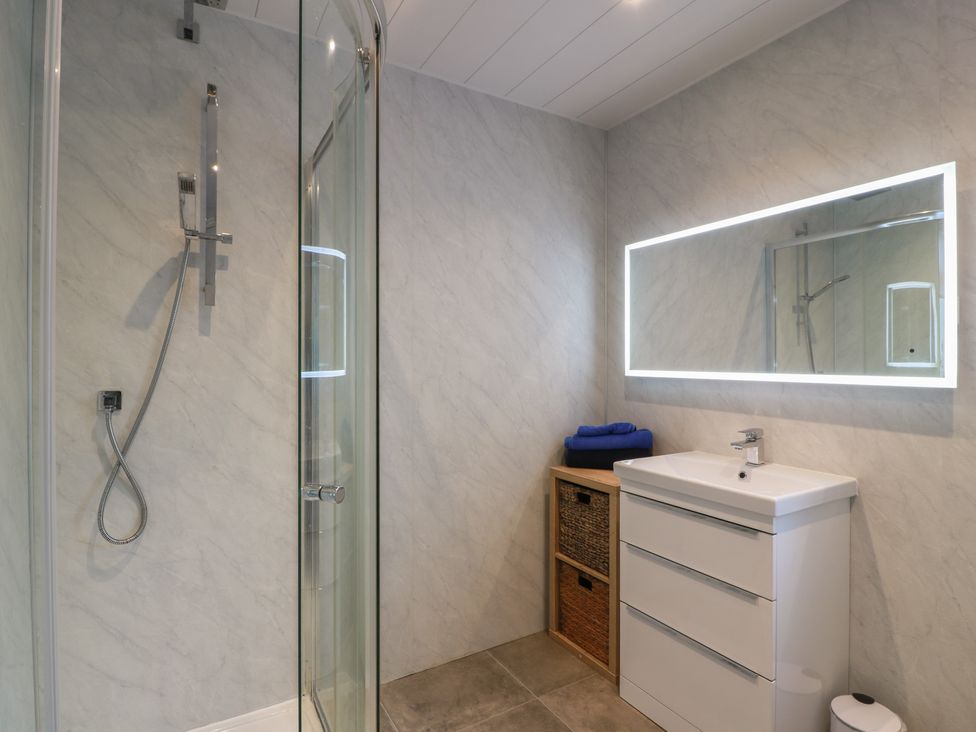 A bathroom featuring a shower, sink, and storage basket at Marchdyke Farm Cottage in Dalton near Annan