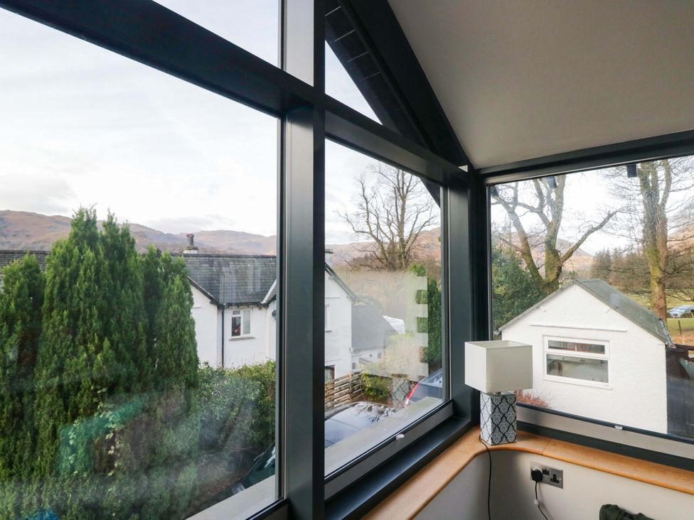 A room with a window view of houses and trees at Two Hollens in Ambleside