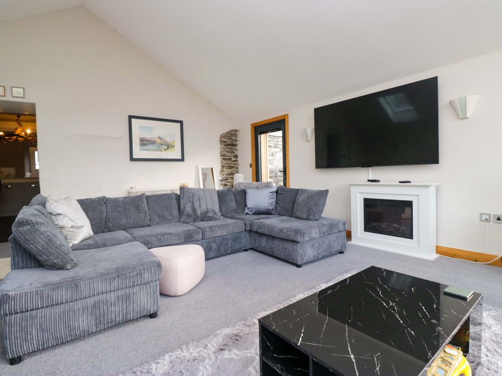 A living room with a grey sofa and television at Two Hollens in Ambleside
