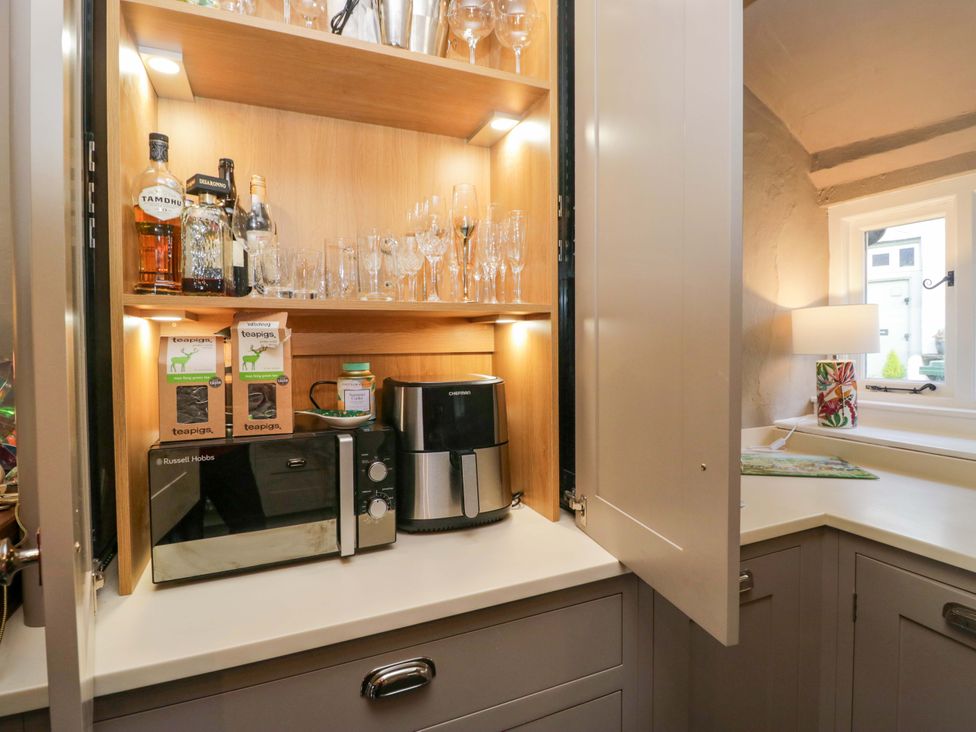 A kitchen with a cabinet containing drinks and appliances at Two Hollens in Ambleside