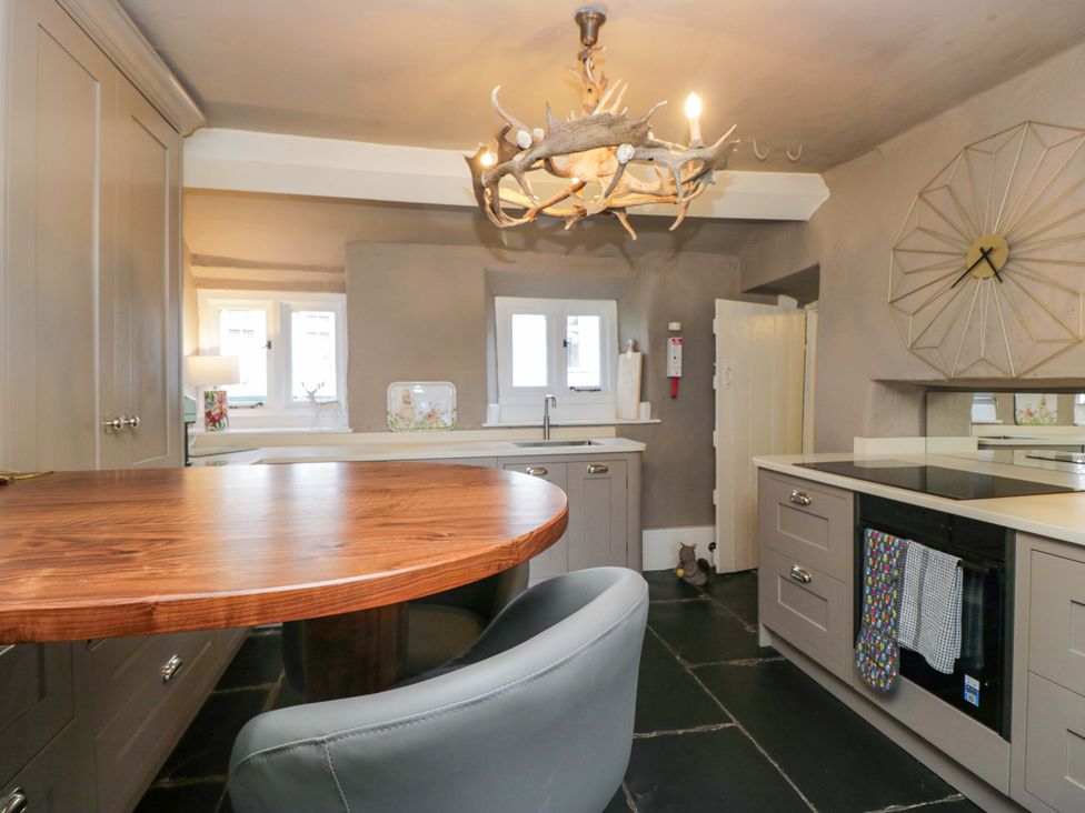 A kitchen with a wooden table and gray cabinets at Two Hollens in Ambleside