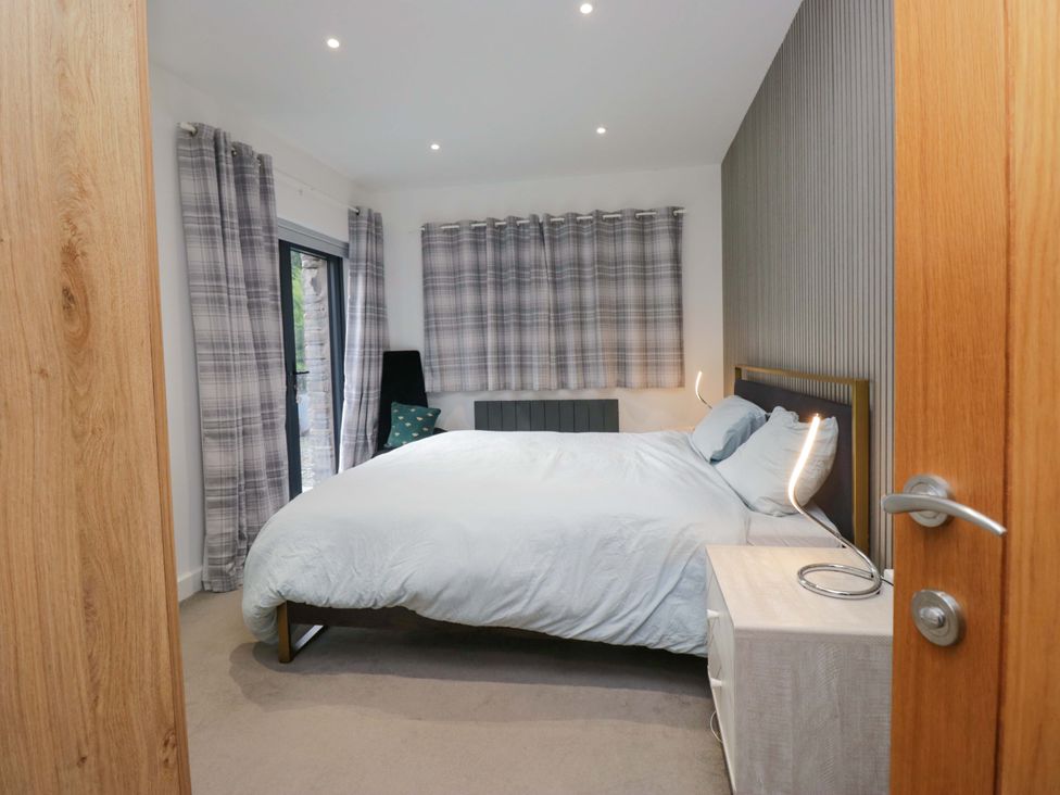 A bedroom with a bed and curtains at Two Hollens in Ambleside