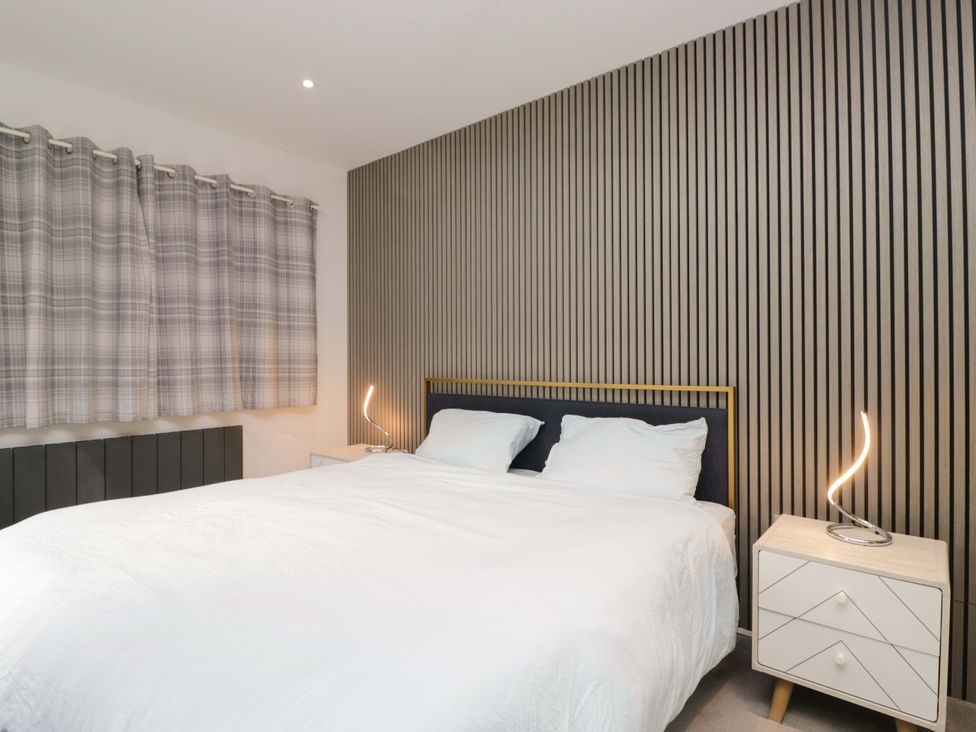 A bedroom with a bed and bedside table at Two Hollens in Ambleside