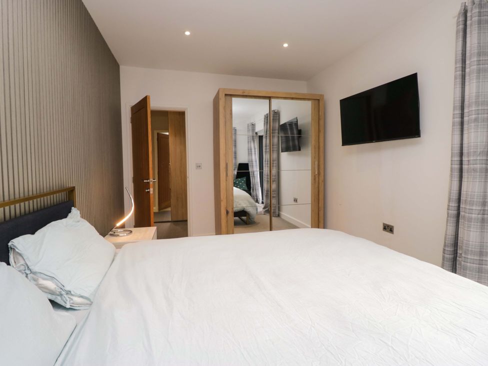 A bedroom featuring a bed, mirror, and television at Two Hollens in Ambleside