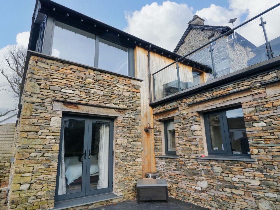 An exterior view of a property with stone walls and glass features at Two Hollens in Ambleside