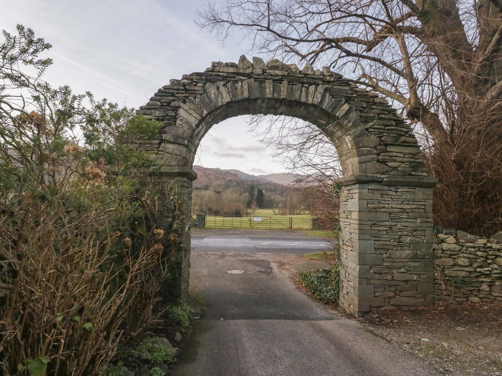 A stone archway with shrubbery and a field beyond at Two Hollens in Ambleside
