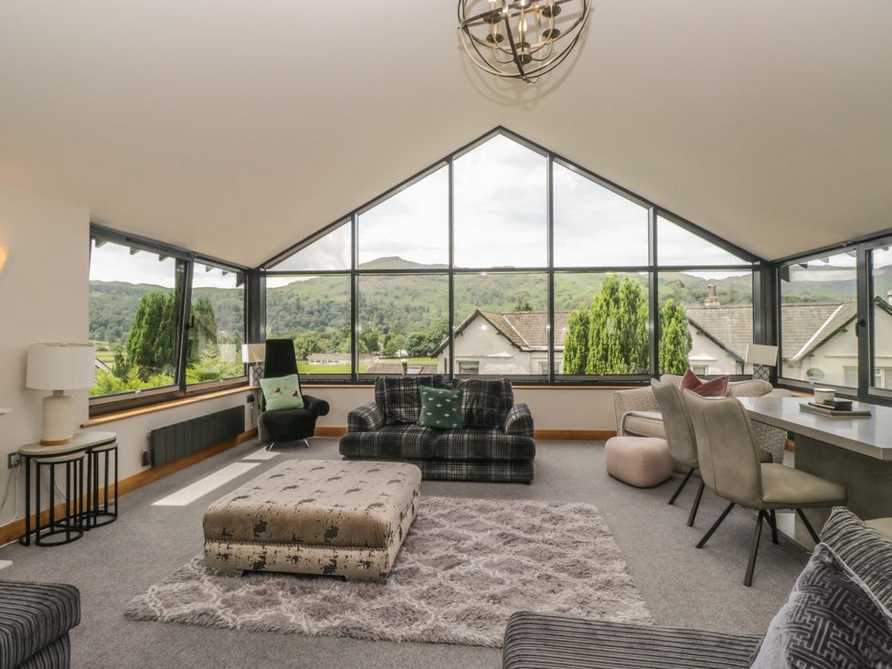 A living room with a sofa and large windows at Two Hollens in Grasmere