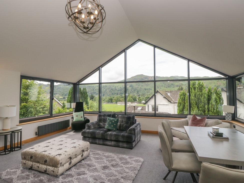 A living room with large windows and seating at Two Hollens in Grasmere