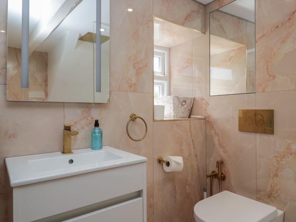 A bathroom with a sink, mirror, and toilet at Two Hollens in Grasmere