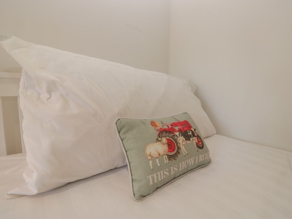 A bed with a white pillow and a decorative pillow at Two Hollens in Grasmere