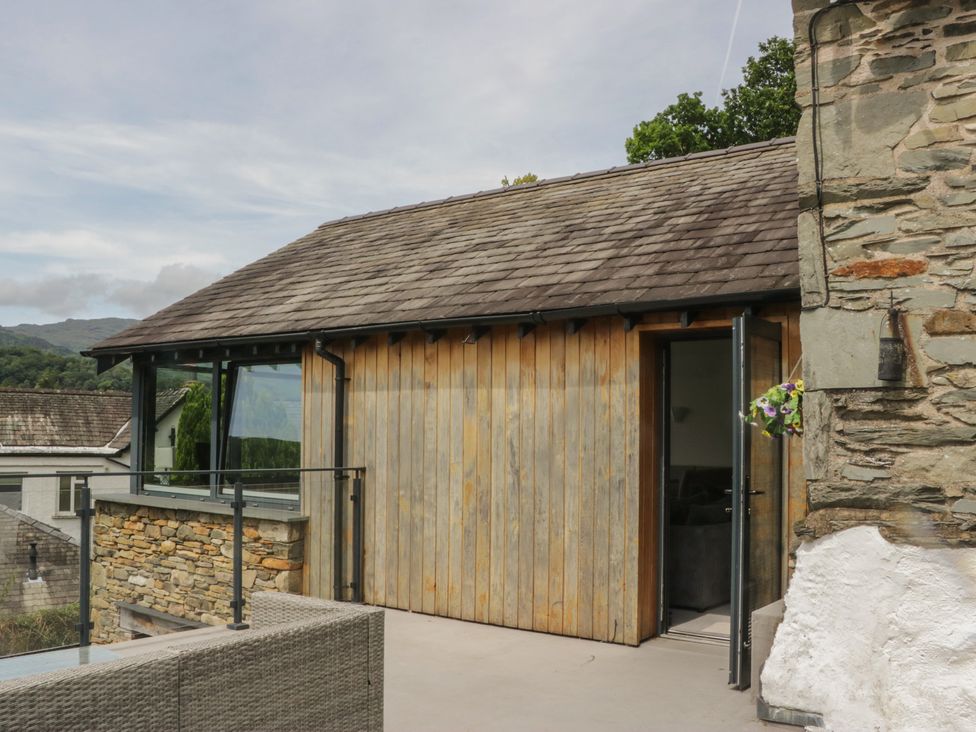 An outdoor area with a stone wall and wooden structure at Two Hollens in Grasmere