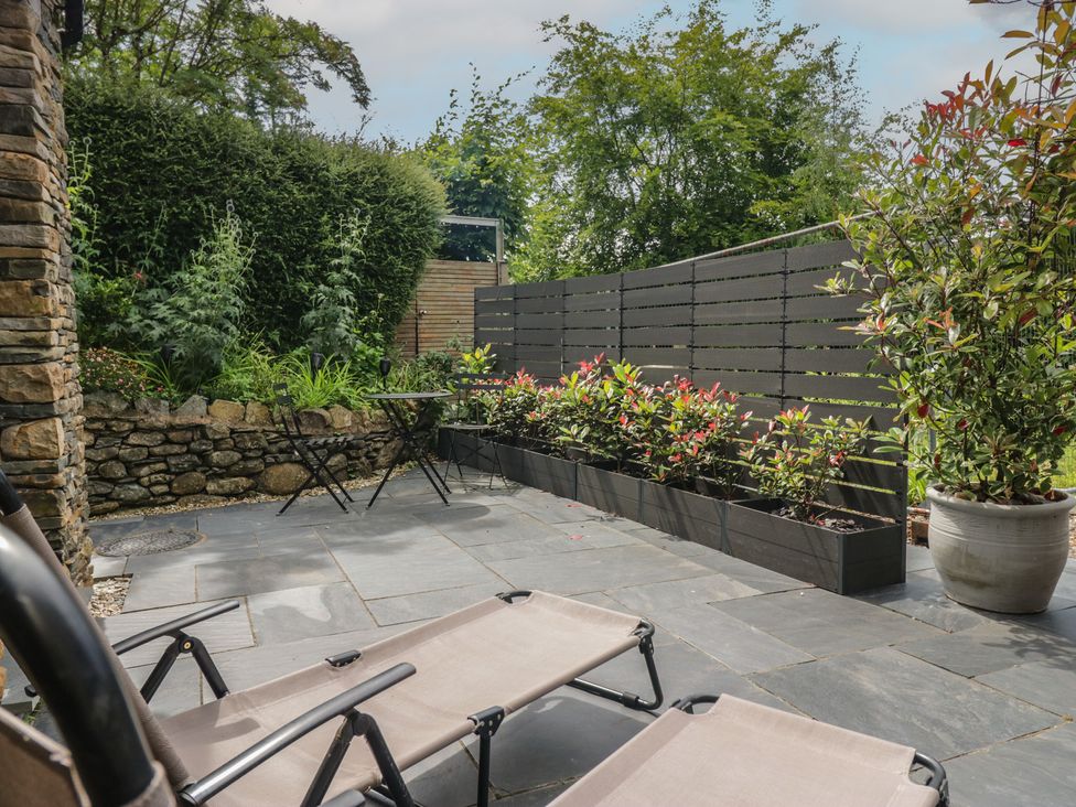 A patio with sun loungers and flower beds at Two Hollens in Grasmere
