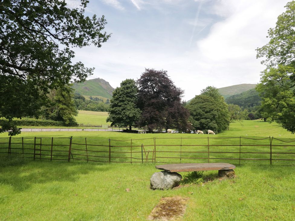 A grassy area with a stone table and sheep near trees at Two Hollens in Grasmere