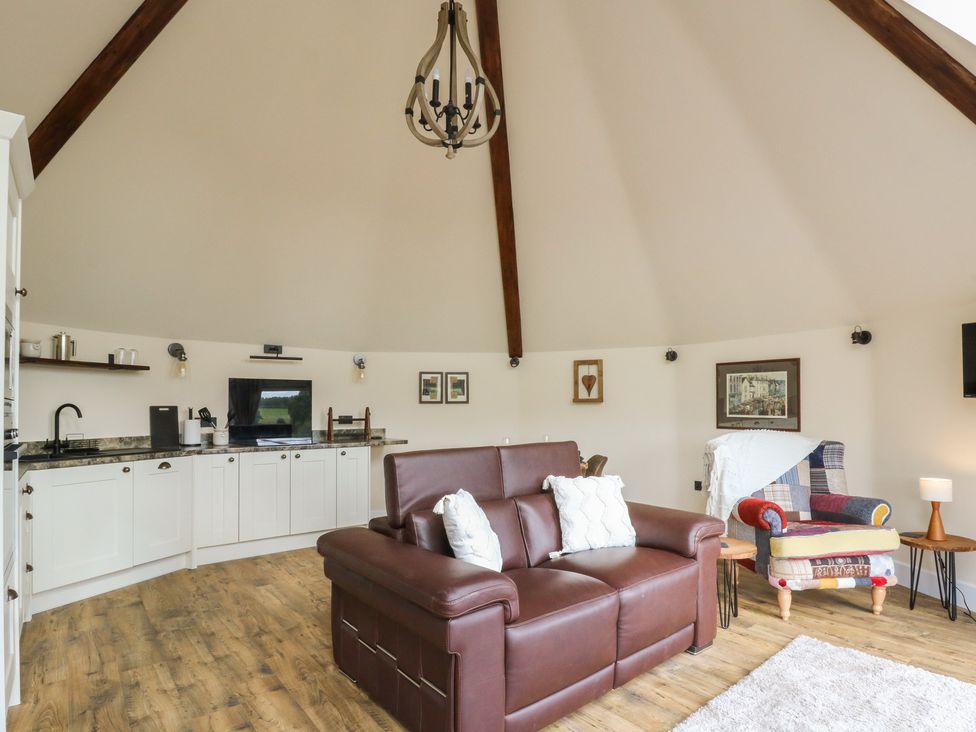 A living room with a sofa and kitchen area at Yr Awen in Lampeter