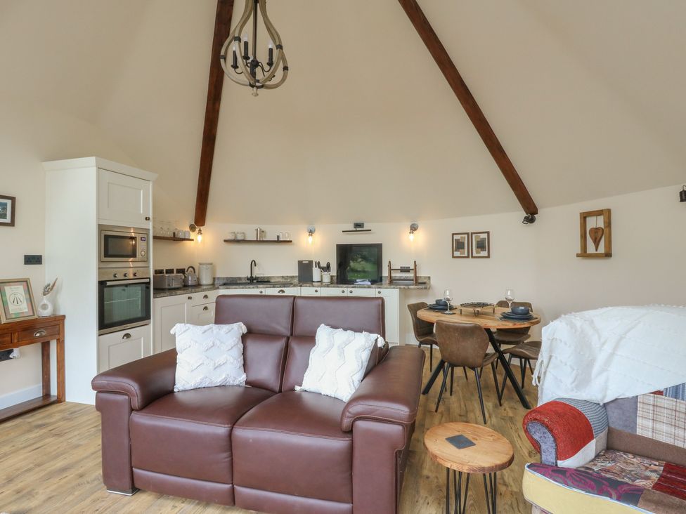 A living room with a sofa and dining area at Yr Awen in Lampeter