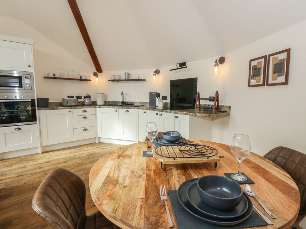 A kitchen with dining area and appliances at Yr Awen in Lampeter