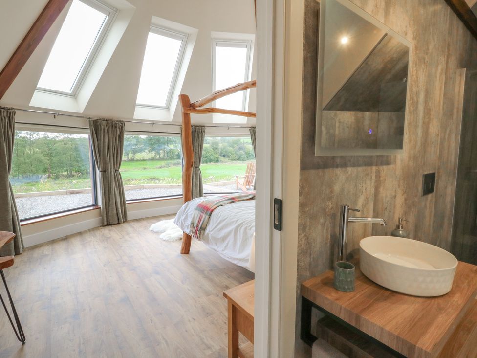 A bedroom with a bed and a bathroom sink at Yr Awen in Lampeter