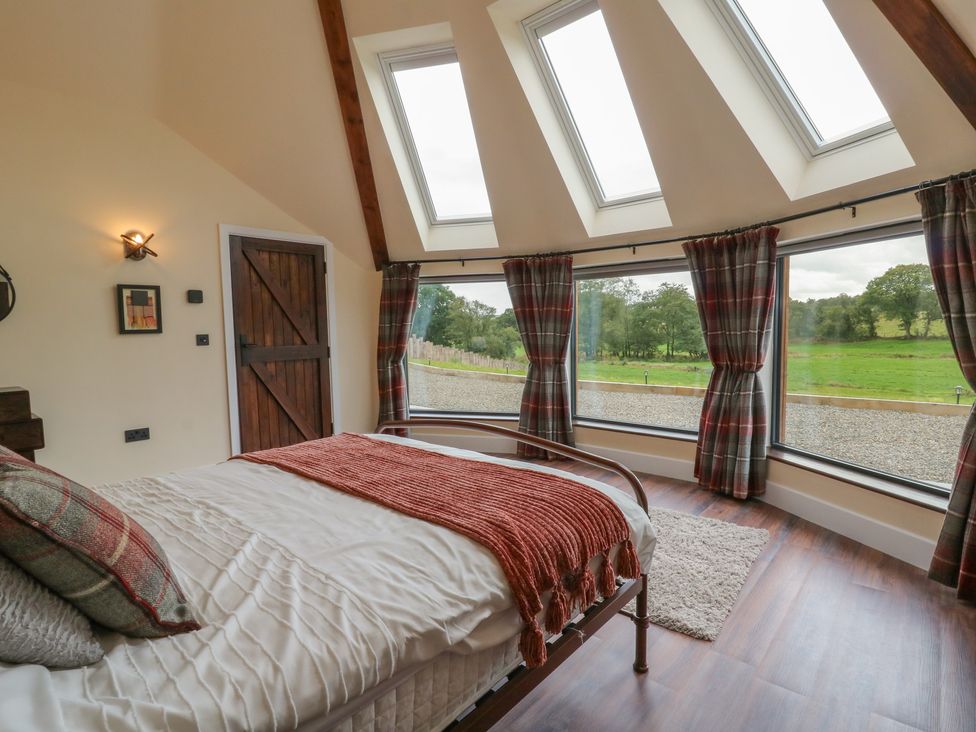 A bedroom with a bed and large windows at Y Cwlwm in Lampeter