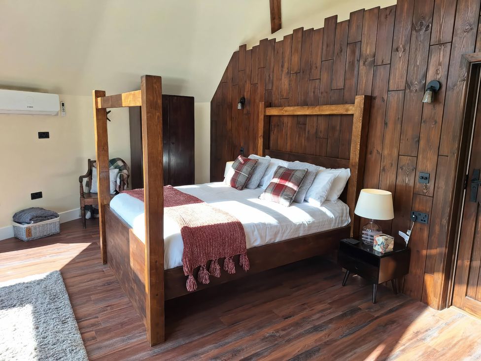 A bedroom with a wooden bed and nightstand at Y Cwlwm - The Celtic Knot near Lampeter