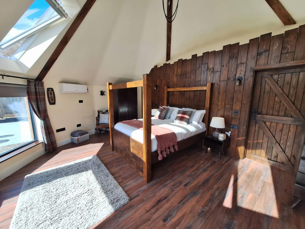 A bedroom with a wooden bed and window at Y Cwlwm - The Celtic Knot Near Lampeter