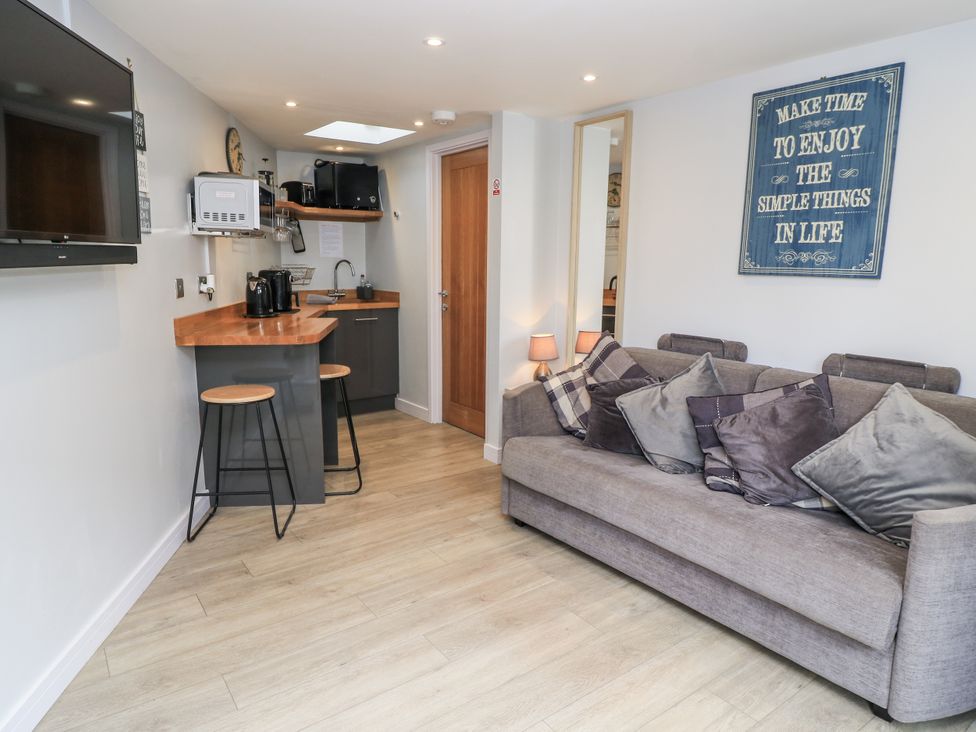A living room with a sofa and kitchen counter at The Chill Garden Room in Shepton Mallet