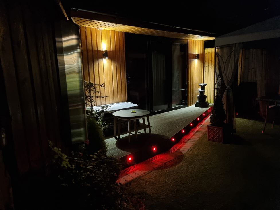 An outdoor deck with a table and water fountain at The Chill Garden Room Shepton Mallet