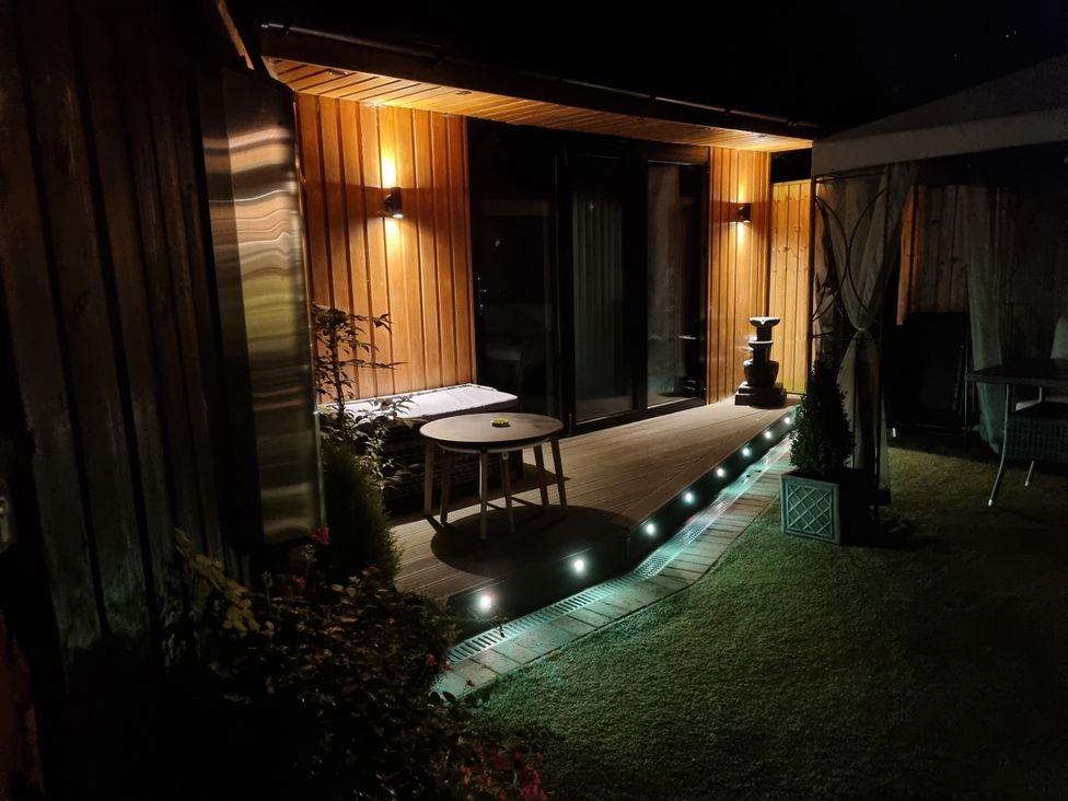 A garden with a deck and table at The Chill Garden Room in Shepton Mallet