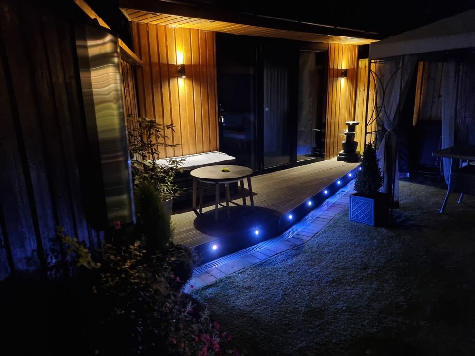 An outdoor deck area with a table and water feature at The Chill Garden Room in Shepton Mallet
