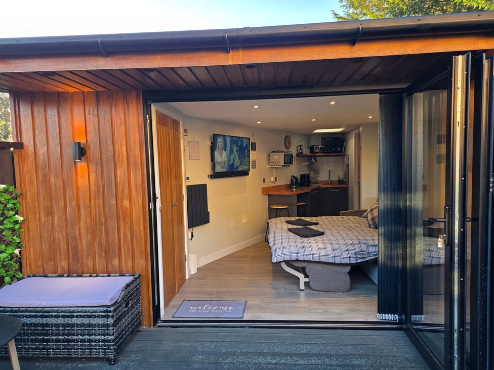 A studio with a bed, kitchenette, and television at The Chill Garden Room in Shepton Mallet