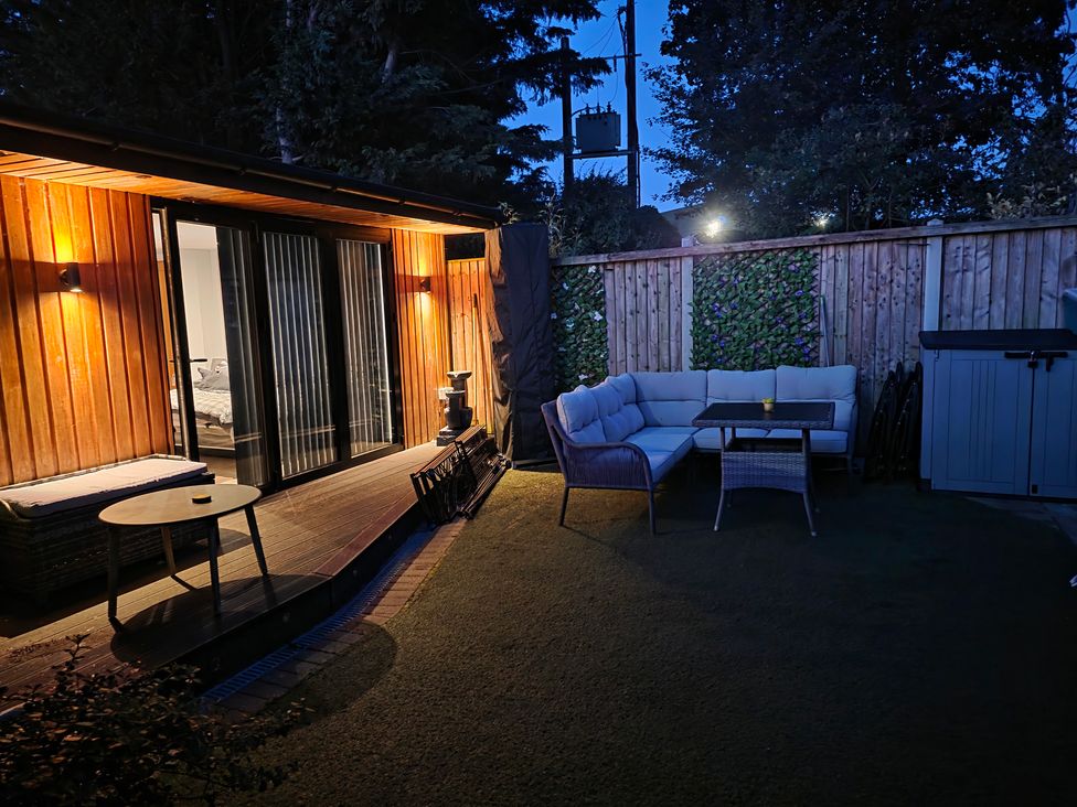 A garden with seating and a storage shed at The Chill Garden Room in Shepton Mallet