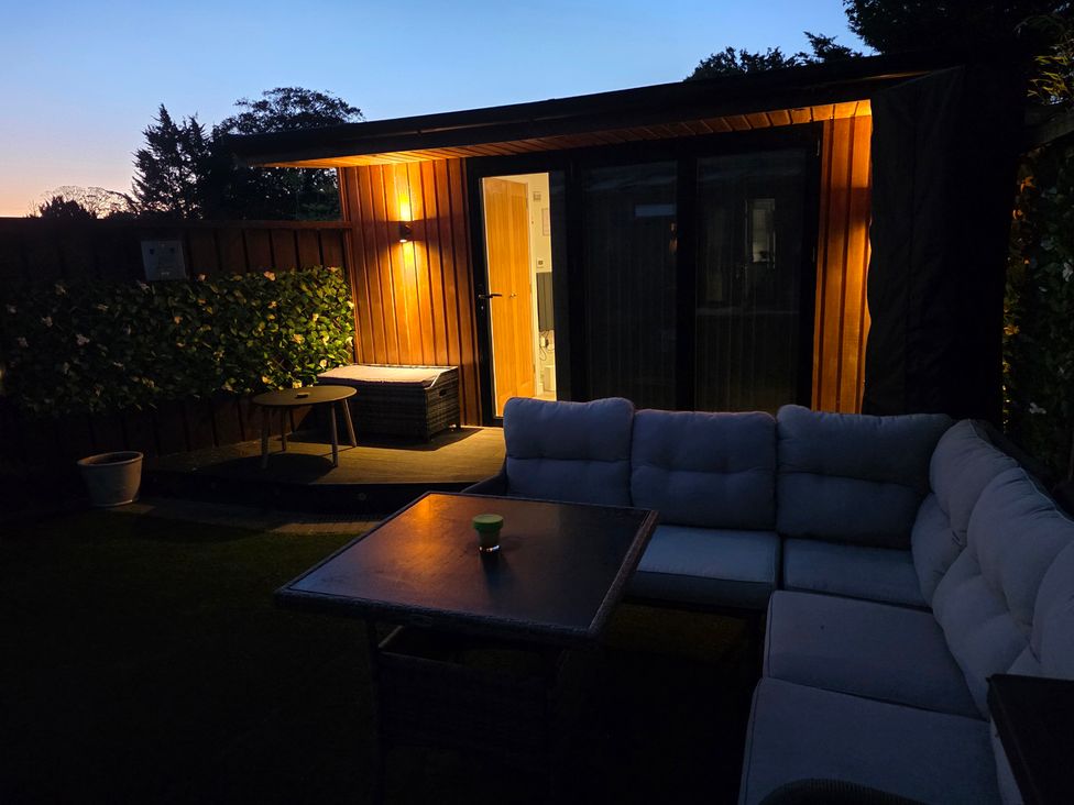 A garden with a sofa and table at The Chill Garden Room in Shepton Mallet