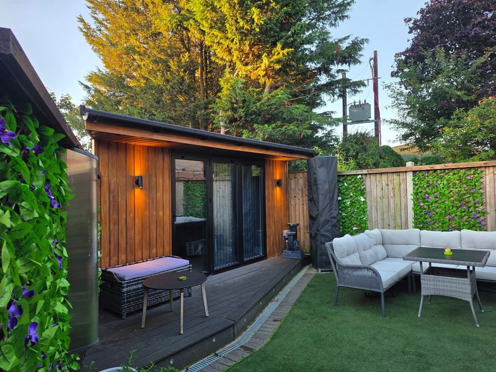 A garden area with a wooden building and seating at The Chill Garden Room in Shepton Mallet