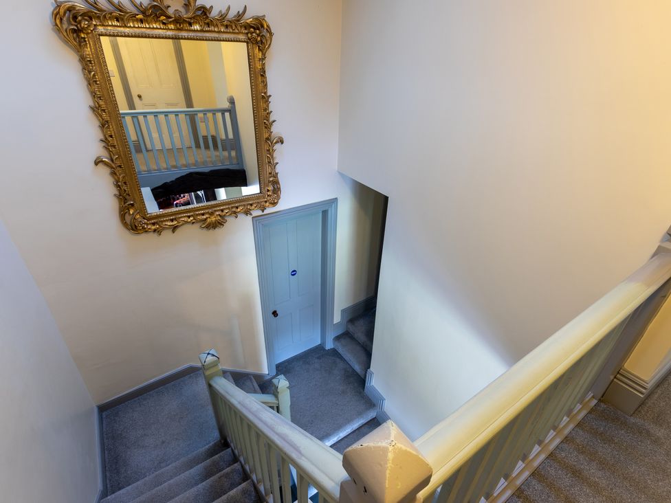 A staircase with a mirror and door at Souterstead Torver near Coniston