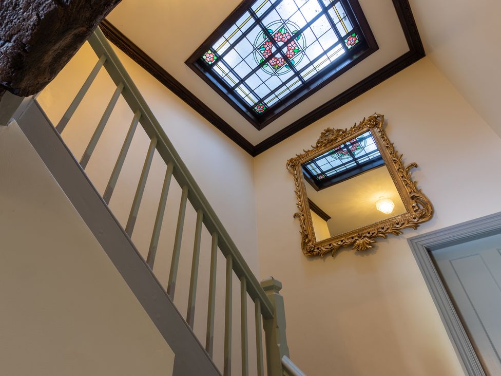A staircase with a stained glass window and mirror at Souterstead in Torver near Coniston