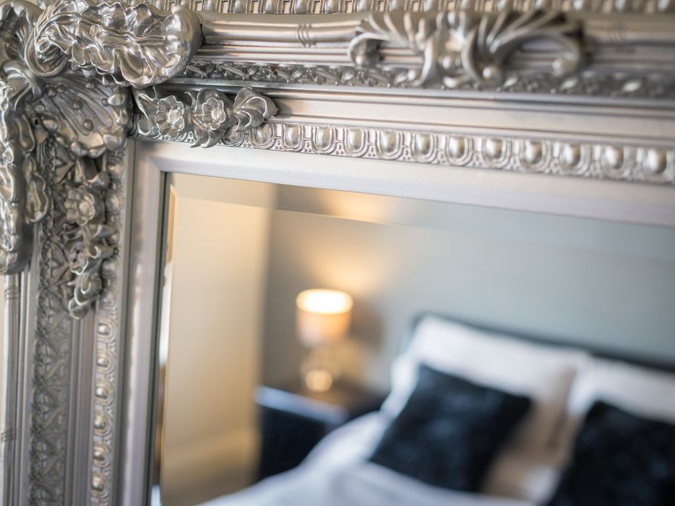 A mirror reflecting a bedside table and bed at Souterstead in Torver near Coniston