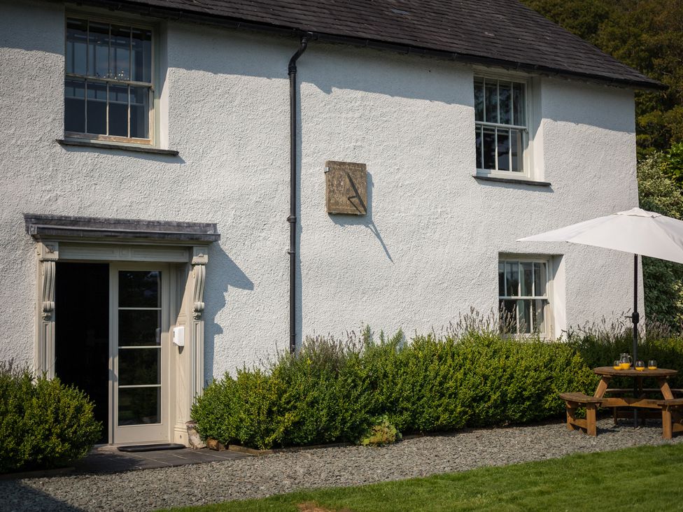 A house facade with a door, windows, and a table with an umbrella at Souterstead in Torver near Coniston