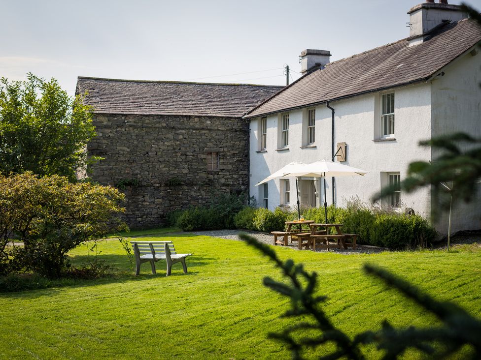 An outdoor area with a house, bench, table, and umbrella at Souterstead in Torver near Coniston