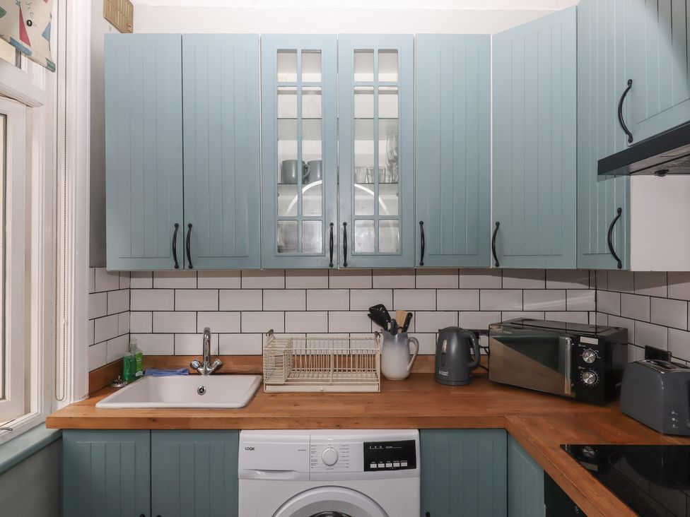 A kitchen with cabinets, sink, washing machine, and kitchen appliances at Home by the Harbour in Dartmouth