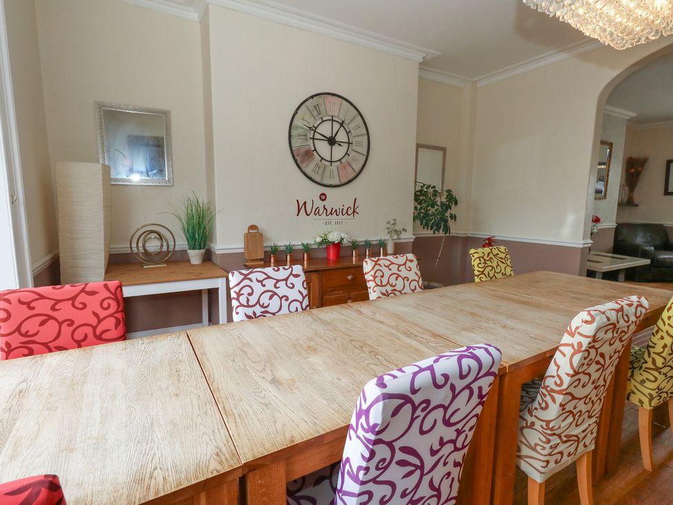 A dining room with a large table and colorful chairs at 9 The Esplanade