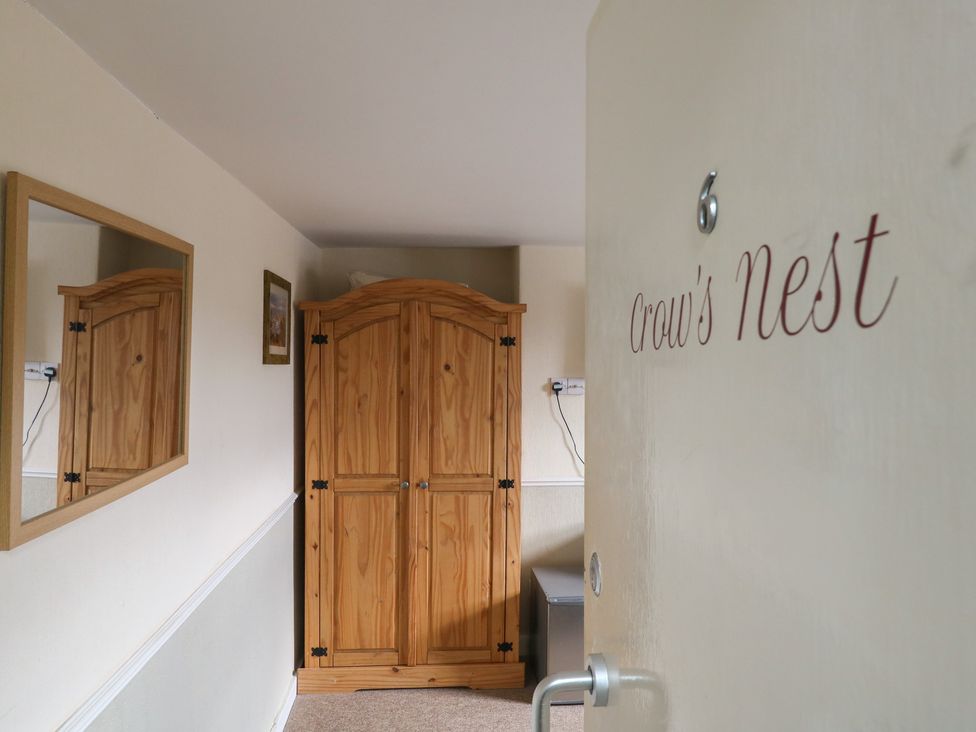 A hallway with a wooden wardrobe and mirror at Crow's Nest