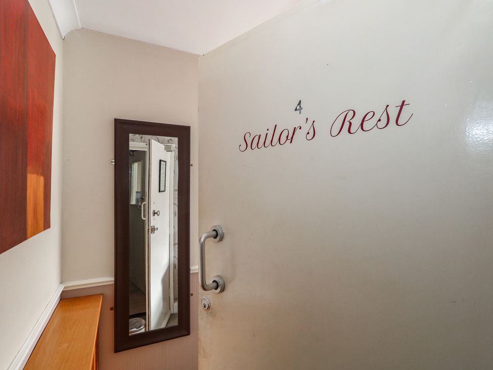 An entryway with a door, mirror, and table at Sailor's Rest