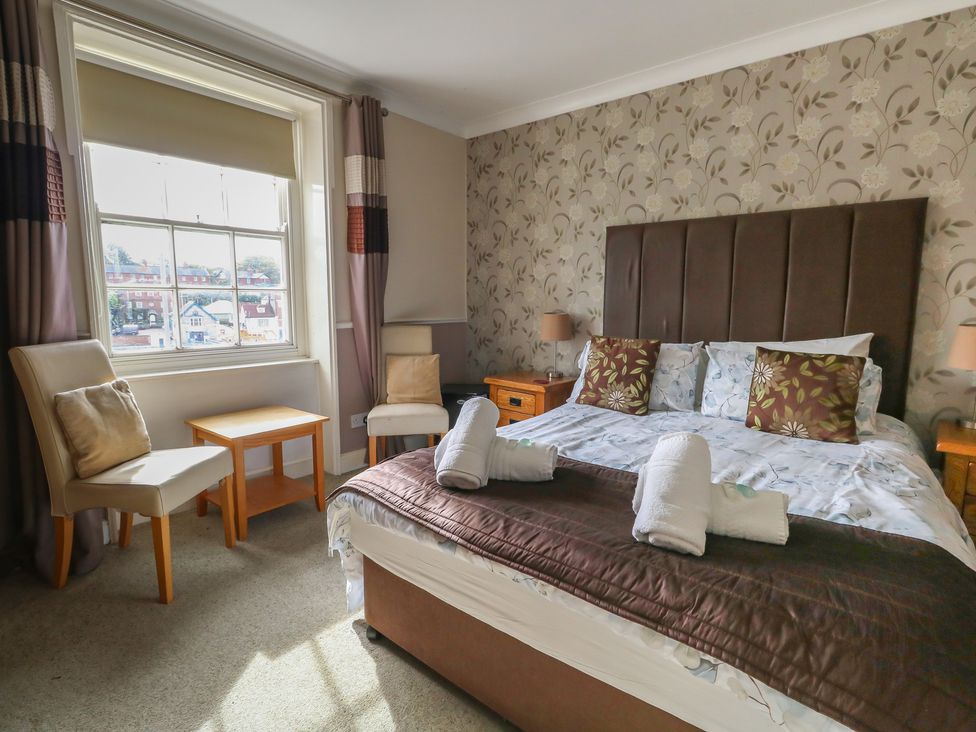 A bedroom with a bed and chairs at 9 The Esplanade