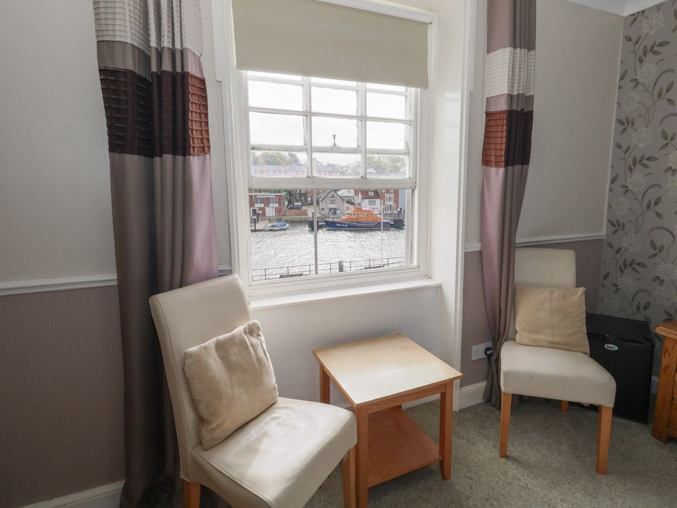 A seating area with chairs and a table overlooking the water at 9 The Esplanade