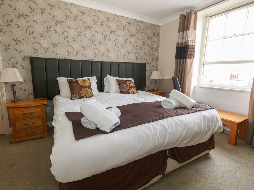 A bedroom with a bed, bedside tables, and a window at 9 The Esplanade