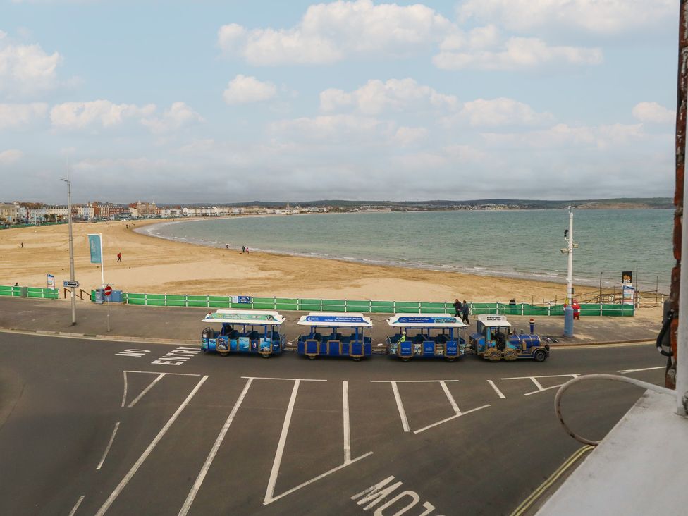 A beach with sand and a train on the road at 9 The Esplanade